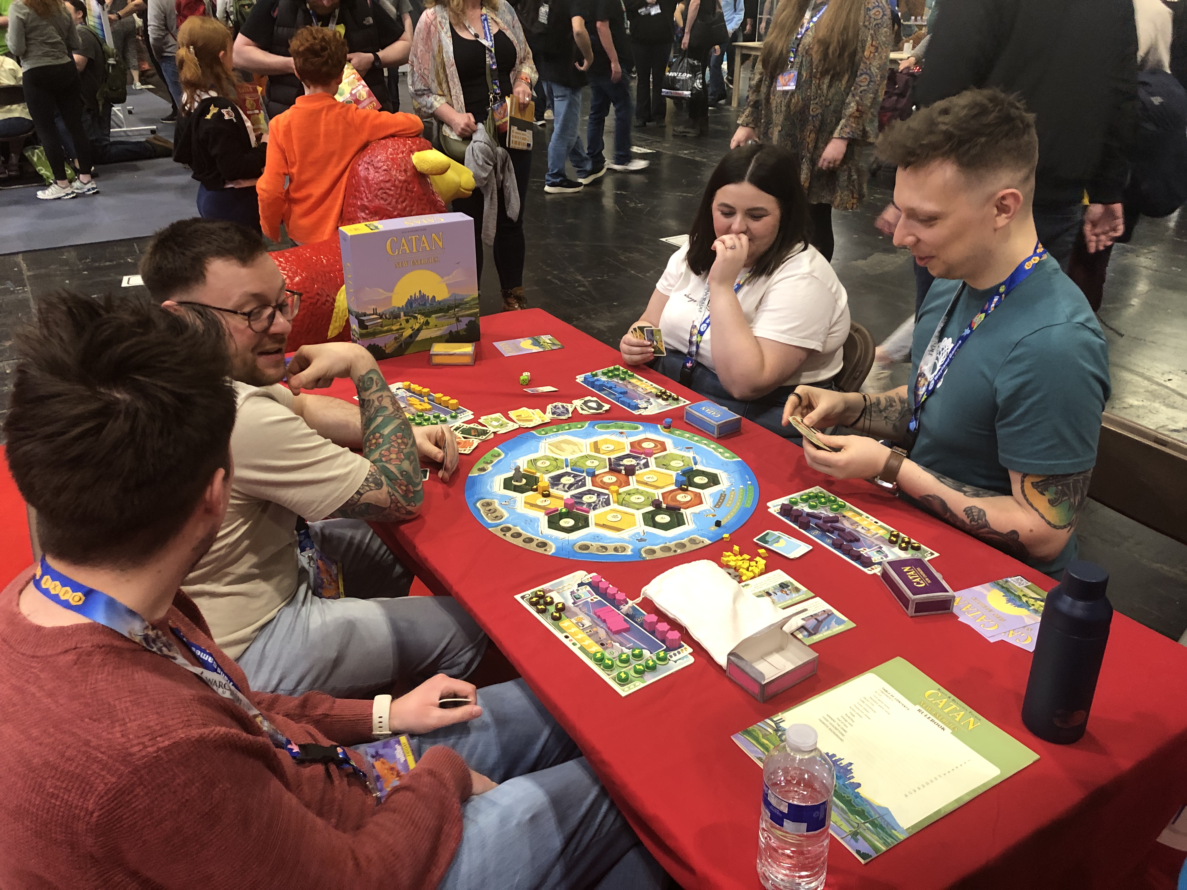 A group of four people sitting down at a table playing CATAN – New Energies.